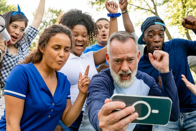 Kibice obserwujący, jak ich drużyna wygrywa mecz na telefonie komórkowym