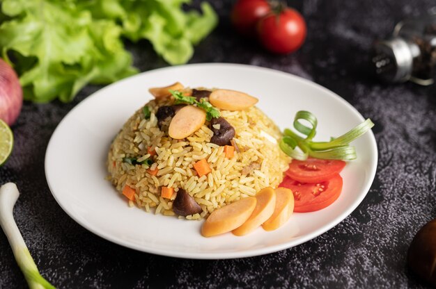 Kiełbasa smażony ryż z pomidorami, marchewką i grzybami shiitake na talerzu