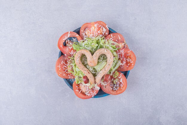 Kiełbasy gotowane w kształcie serca i plastry pomidora.
