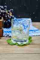 Bezpłatne zdjęcie kieliszek białego wina na drewnianym stole z winogronami. wysokiej jakości zdjęcie