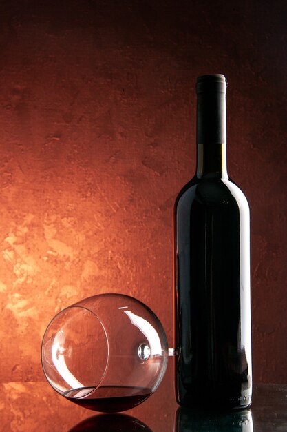 Kieliszek do wina z widokiem z przodu z butelką wina na ciemnym kolorze szampana świąteczny napój alkoholowy