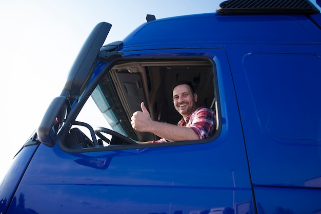 Kierowca ciężarówki pokazuje kciuki przez okno kabiny