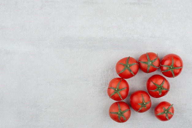 Kilka czerwonych pomidorów na białym tle.