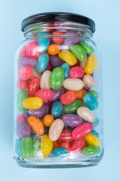 Kilka Jelly Beans na niebieskim tle w szklanym garnku