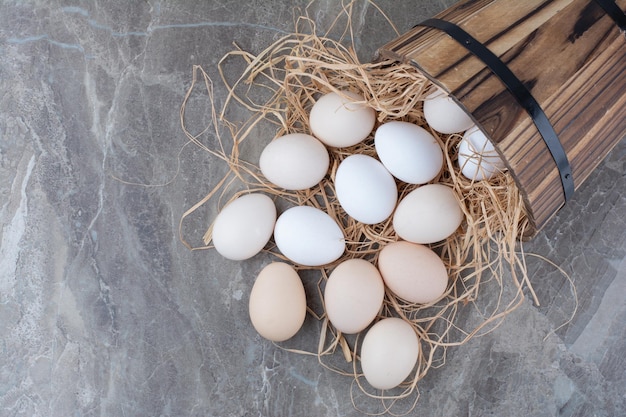 Kilka świeżych jaj kurzych na siano na marmurowym tle. zdjęcie wysokiej jakości
