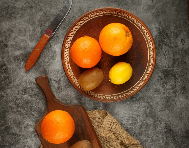 Bezpłatne zdjęcie kiwi, pomarańcze i cytryna w misce. widok z góry.