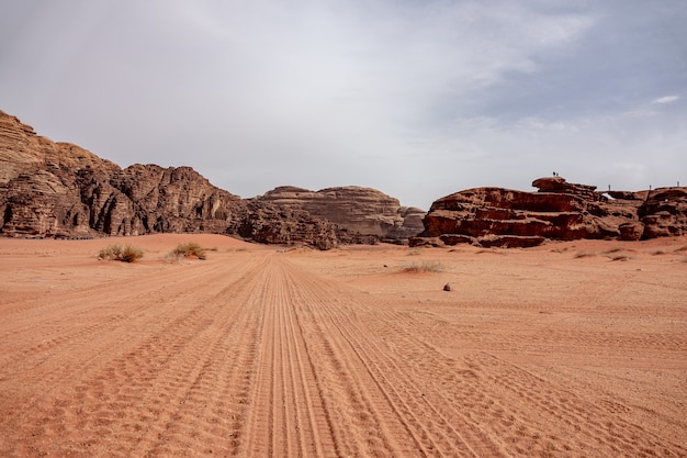 Klify i jaskinie na pustyni pełnej suchej trawy pod zachmurzonym niebem w ciągu dnia