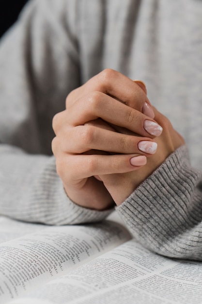 Kobiece ręce w pozycji modlitwy z Biblią