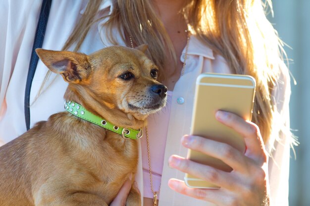 Kobiet z psem na rękach wykorzystaniem smartphone