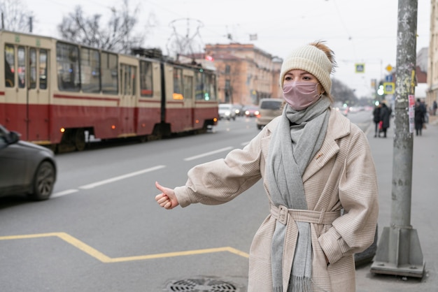 Bezpłatne zdjęcie kobieta autostopem w mieście w masce