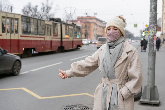 Kobieta autostopem w mieście w masce