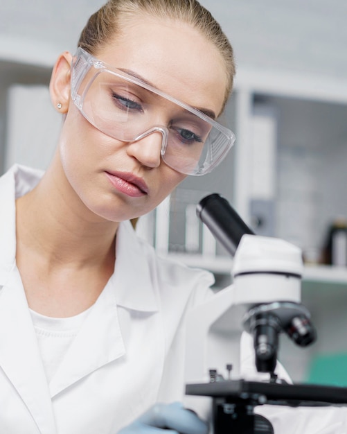 Kobieta badacz w laboratorium z okularami ochronnymi i mikroskopem