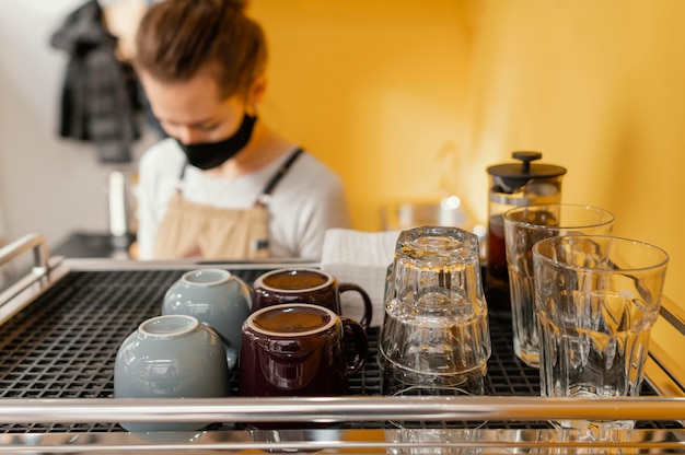 Bezpłatne zdjęcie kobieta barista z maską pracuje w kawiarni