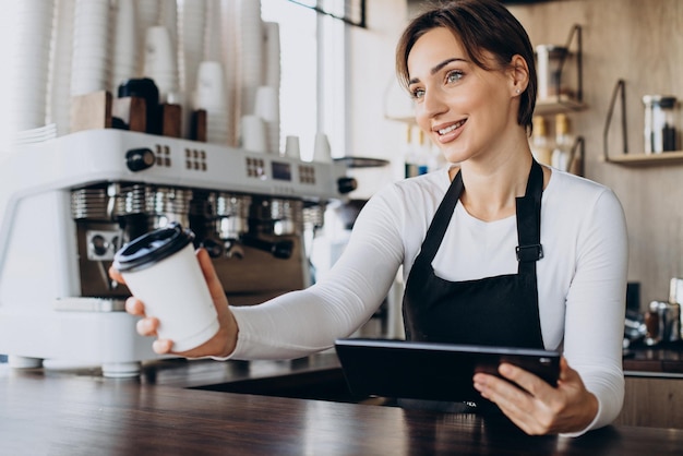Kobieta barista z tabletem robi zamówienie w kawiarni