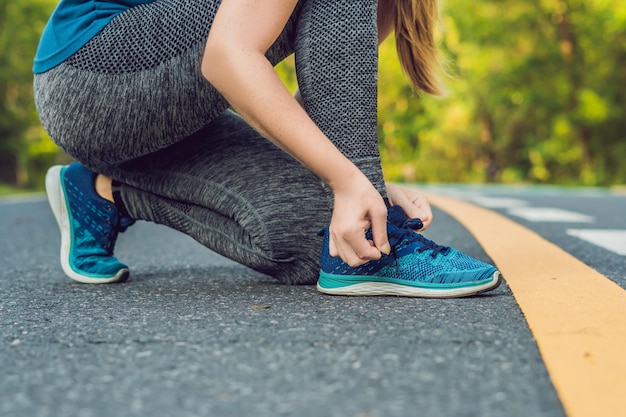 Kobieta biegacz wiązanie jej buty przygotowujące do biegania na zewnątrz. młoda dziewczyna biegacz przygotowuje się do treningu. sportowy styl życia