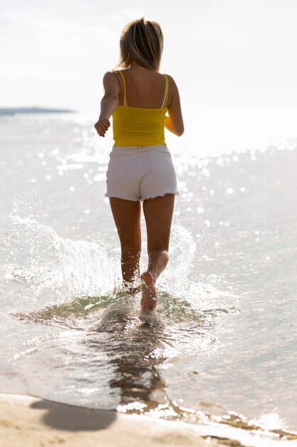 Kobieta biegnąca przez wodę na plaży