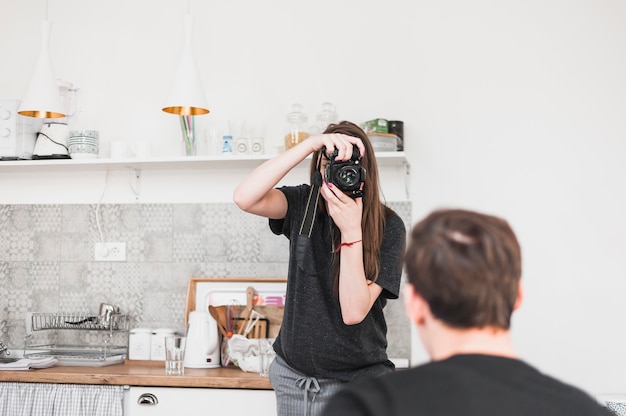 Kobieta bierze fotografię mężczyzna przez kamery w kuchni