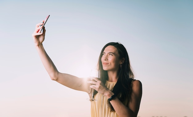 Bezpłatne zdjęcie kobieta bierze selfie w świetle słonecznym