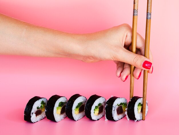 Bezpłatne zdjęcie kobieta biorąc sushi roll pałeczkami