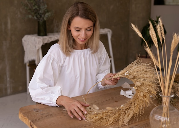 Kobieta budująca własną kompozycję suszonych kwiatów