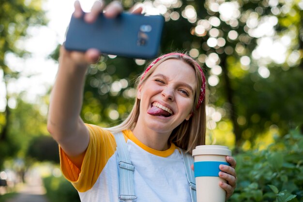 Kobieta buźka, biorąc selfie na zewnątrz