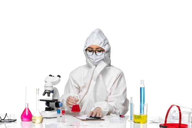 Kobieta Chemik W Specjalnym Kombinezonie Ochronnym, Trzymająca Czerwony Roztwór Na Jasnobiałym Tle Laboratorium Wirusów Covid-chemistry