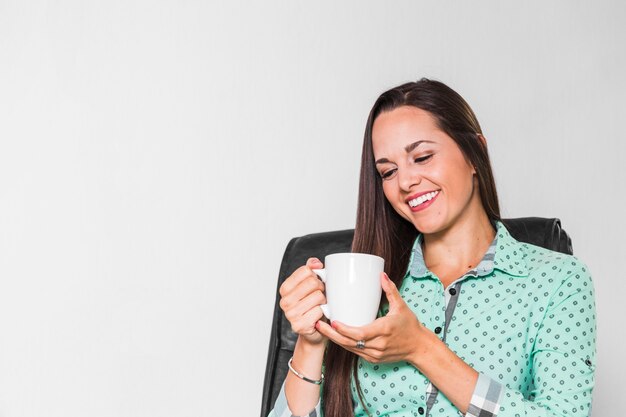 Kobieta cieszy się jej filiżankę kawy przy biurem