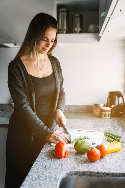 Kobieta ciie warzywa na ciapanie desce