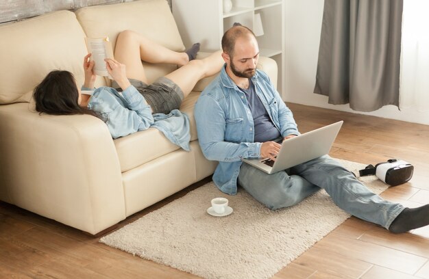 Kobieta czytająca książkę leżącą na kanapie w salonie