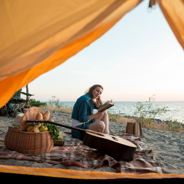 Kobieta czytająca książkę przed namiotem