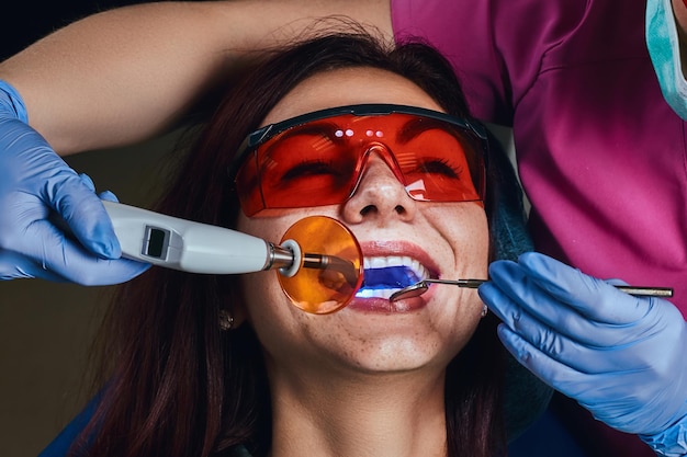 Kobieta Dentysta Lecząca Pacjenta. Close-up Zdjęcie Młodej Kobiety Siedzącej Na Fotelu Dentystycznym.