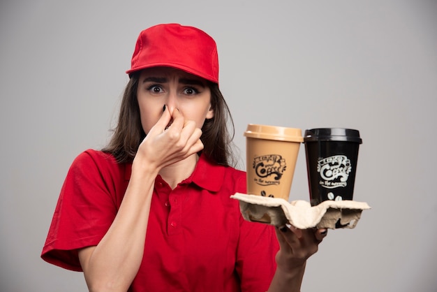 Bezpłatne zdjęcie kobieta dostawy w czerwonym mundurze mocno trzymając nos z powodu zapachu.