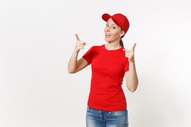 Kobieta dostawy w czerwonym mundurze na białym tle. profesjonalna kobieta kaukaska w czapce, koszulce, dżinsach, pracująca jako kurier lub sprzedawca, wskazująca palcem wskazującym aparat na reklamie przestrzeni kopii