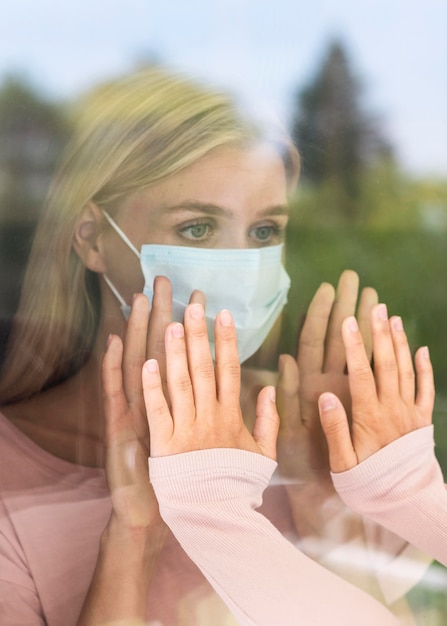 Bezpłatne zdjęcie kobieta dotykająca kogoś rękami przez okno podczas pandemii koronawirusa