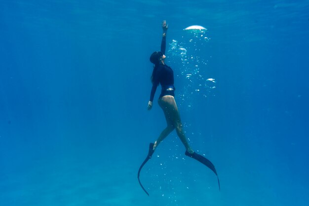 Kobieta freediving z płetwami pod wodą