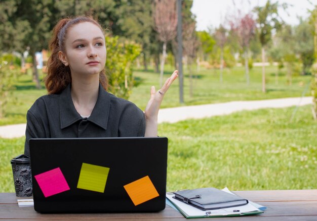 Kobieta freelancer siedząca przy laptopie pracująca patrząc w górę myśląca