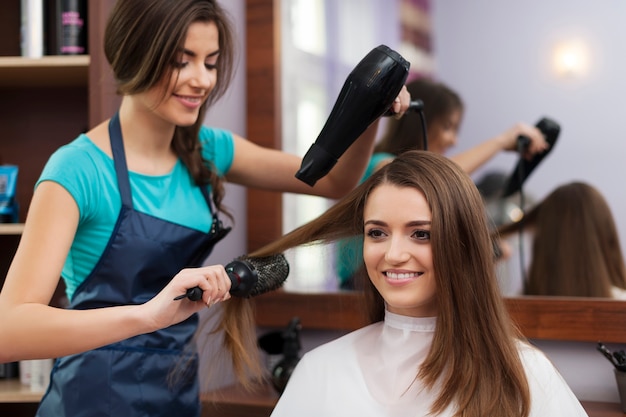 Kobieta fryzjer za pomocą szczotki do włosów i suszarki do włosów