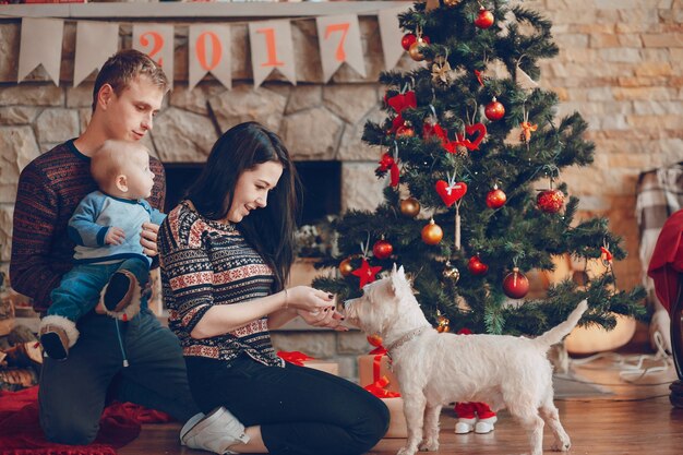 Kobieta głaszcze psa, podczas gdy jej mąż trzyma dziecko w ramionach, na Boże Narodzenie
