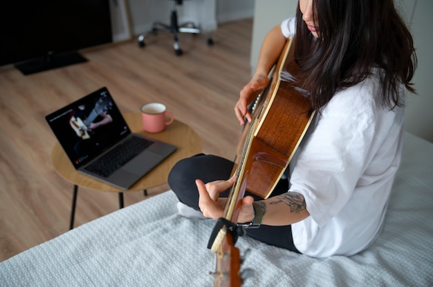 Bezpłatne zdjęcie kobieta gra na gitarze w domu podczas kwarantanny