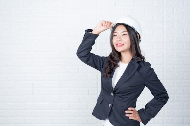 Kobieta inżynierii trzyma kapelusz, Oddziel białe ściany z cegły wykonane gesty z języka migowego.