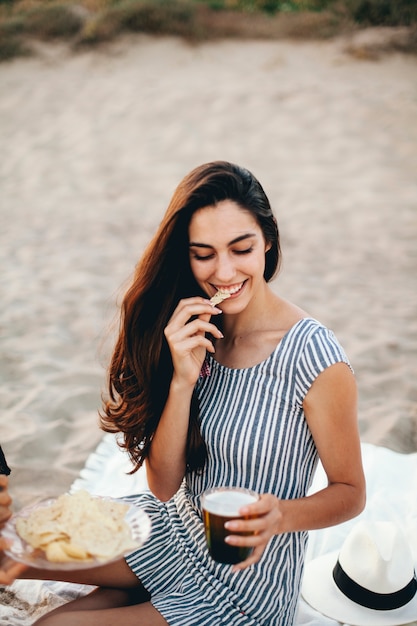 Bezpłatne zdjęcie kobieta jedzenia nacho en la playa