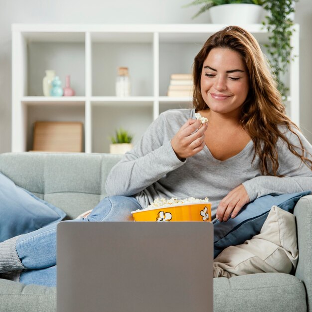 Kobieta jedzenie popcornu, patrząc na laptopa