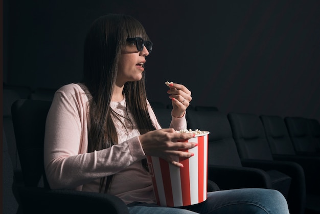 Kobieta, jedzenie popcornu w kinie