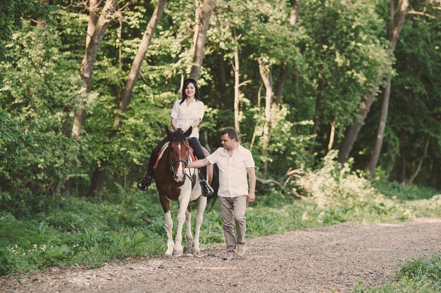 Kobieta jedzie na koniu z mężem na spacer