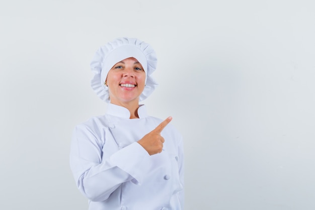 kobieta kucharz, wskazując na prawym górnym rogu w białym mundurze i wyglądająca pewnie