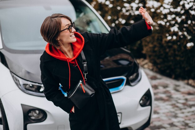 Kobieta ładuje electro samochód jej domem