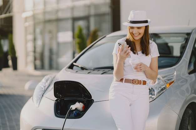 Kobieta ładuje electro samochód przy elektryczną benzynową stacją