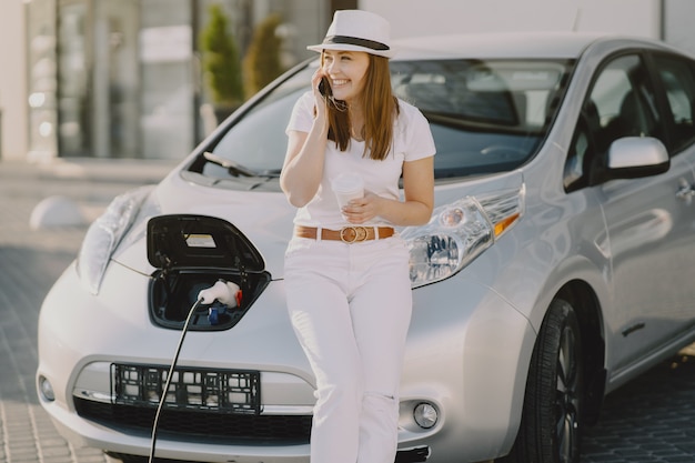 Kobieta ładuje electro samochód przy elektryczną benzynową stacją