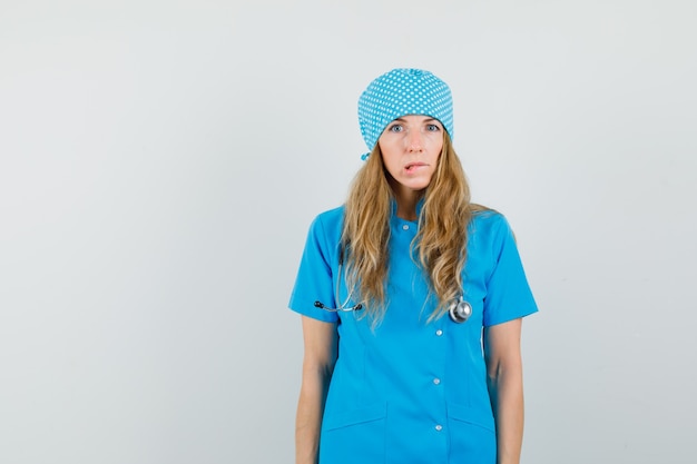 Bezpłatne zdjęcie kobieta lekarz gryzie wargę w niebieskim mundurze i wygląda zapominalski