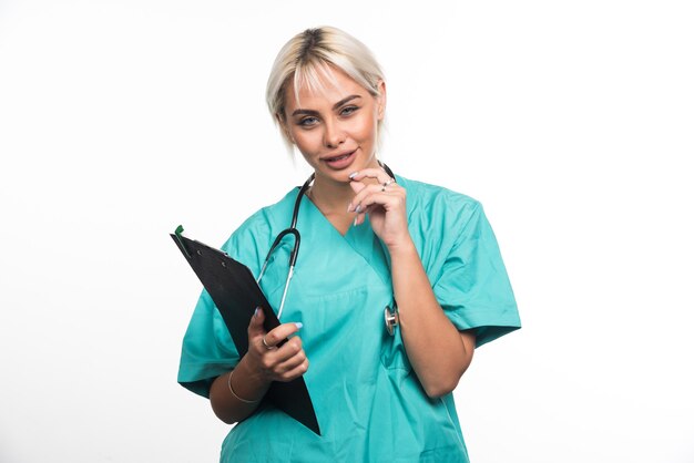 Kobieta lekarz trzymając schowek podczas myślenia na białej powierzchni